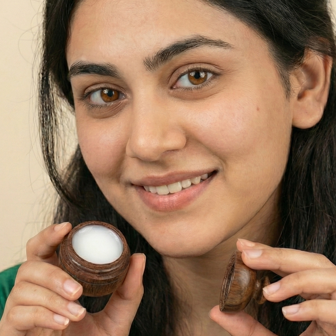 Woman holding two small containers with a beige background