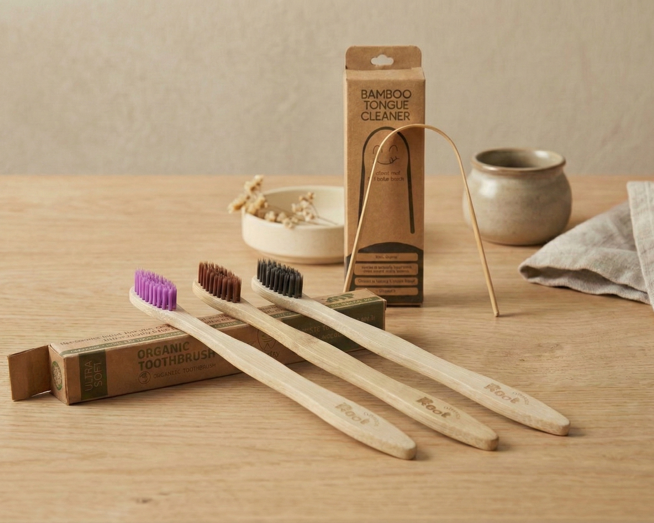 Three bamboo toothbrushes with a packaging box on a wooden surface.